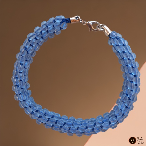 Braccialetto Kumihimo in perline celeste di mezzo cristallo con chiusura argentata su sfondo rosa