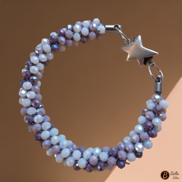 Bracciale Kumihimo in perline miscelate nei toni del bianco, lilla e ametista di vetro sfaccettato e chiusura a stella su fondo rosa 