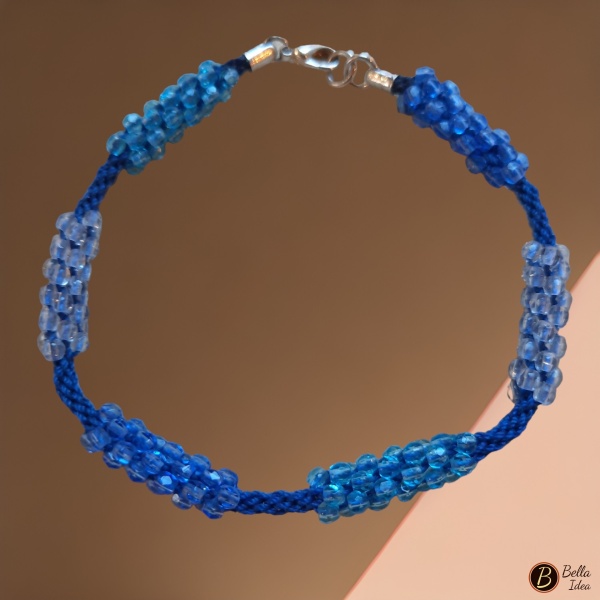 Braccialetto Kumihimo in perline in tre tonalità di azzurro mezzo cristallo su sfondo rosa