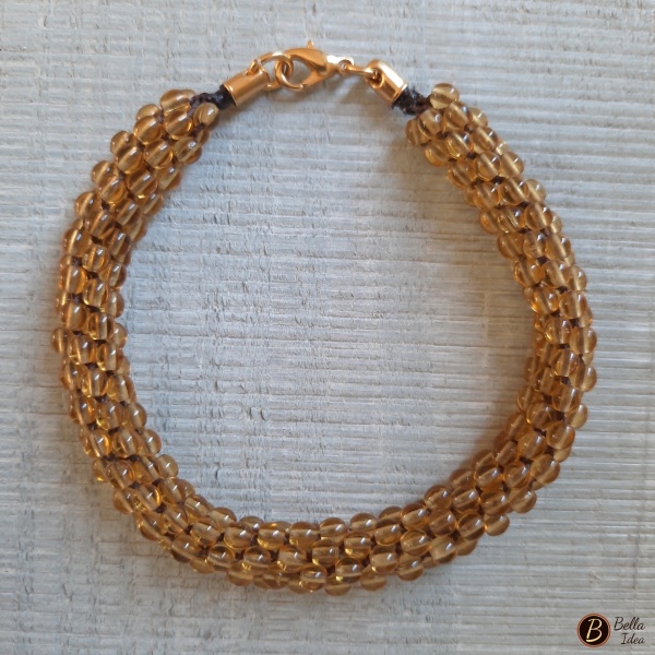 Braccialetto Kumihimo in perline lumè giallo ocra con chiusura a moschettone dorato.