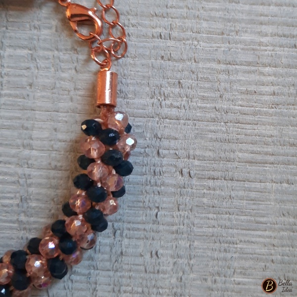 Dettaglio di braccialetto Kumihimo in perline blue e rosa di vetro sfaccettato con chiusura rosè