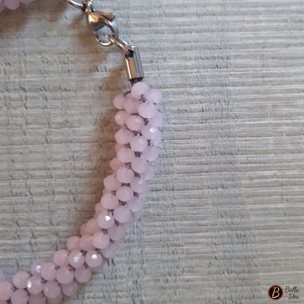 Dettaglio di braccialetto Kumihimo in perline rosa baby di vetro sfaccettato.