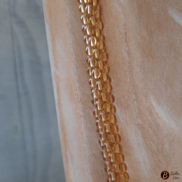 Dettaglio di collana Kumihimo in perline di vetro lumè color giallo ocra con chiusura dorata.