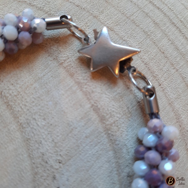 Dettaglio di bracciale Kumihimo in perline miscelate nei toni del bianco, lilla e ametista di vetro sfaccettato e chiusura a stella.