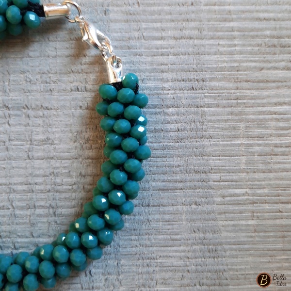 Dettaglio di braccialetto Kumihimo in perline turchese teal di vetro sfaccettato con chiusura argentata