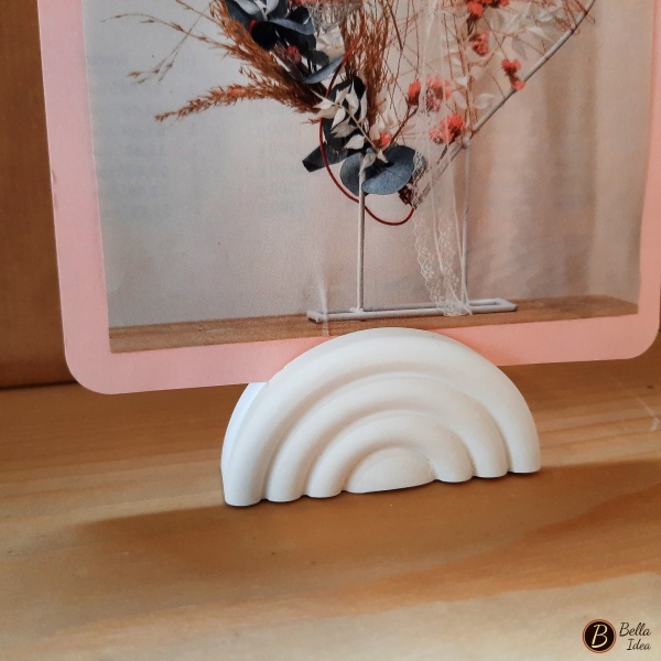 Dettaglio di piccolo arcobaleno in gesso bianco con fessura adatta per fare da supporto a fotografie o biglietti