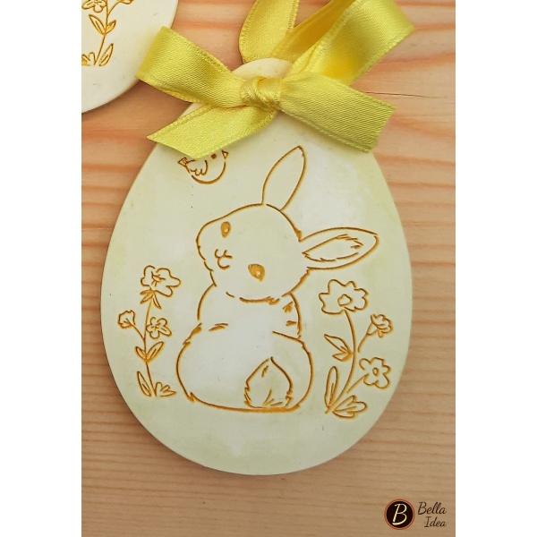 Uovo decorativo in gesso giallo da appendere con coniglietto di schiena 